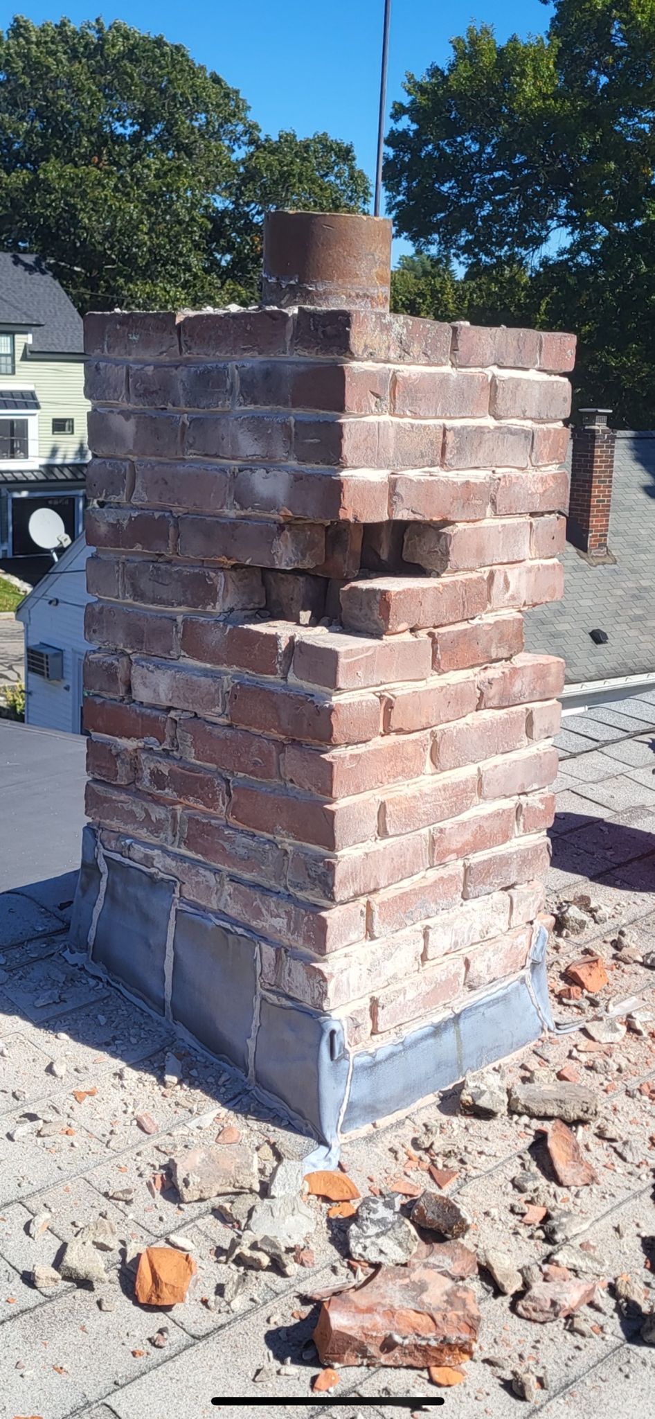 A brick chimney with a hole in it is sitting on top of a roof