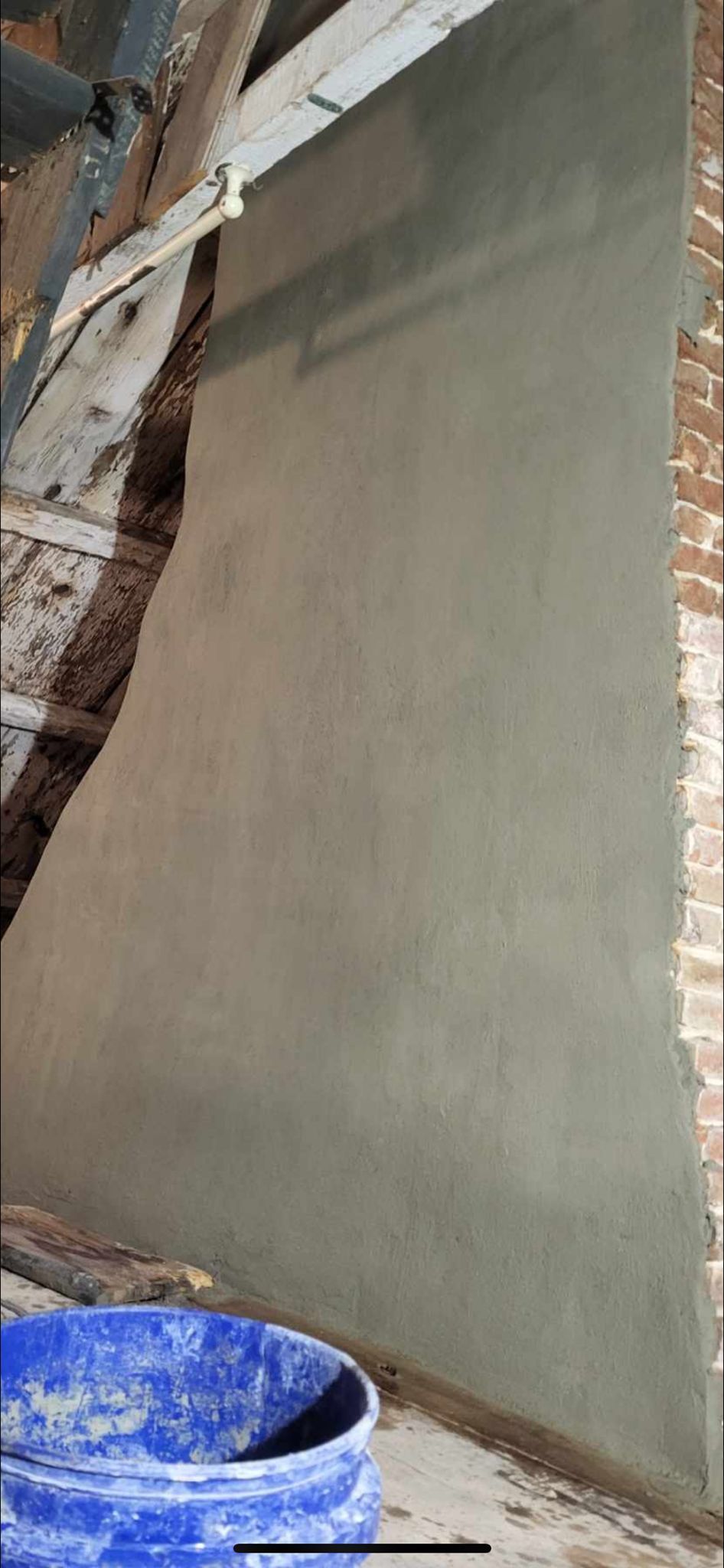 A blue bucket is sitting next to a brick wall