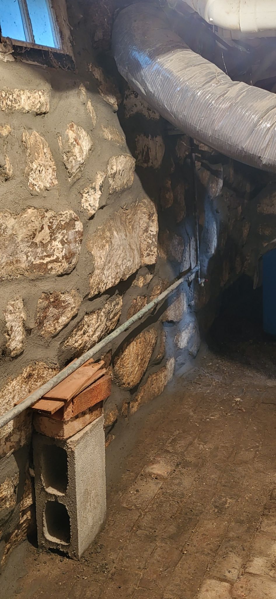 A brick block is sitting on the ground next to a stone wall