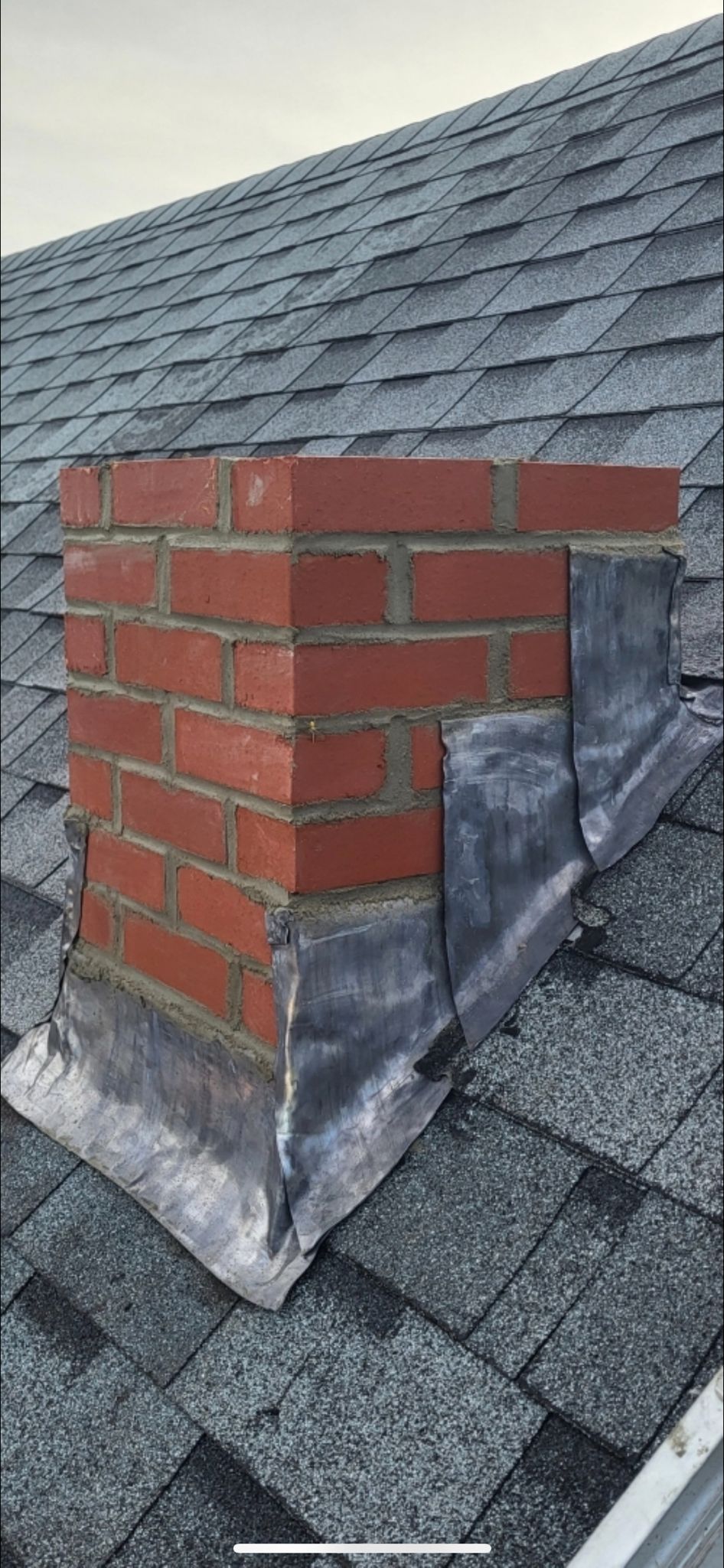 A brick chimney is sitting on top of a roof