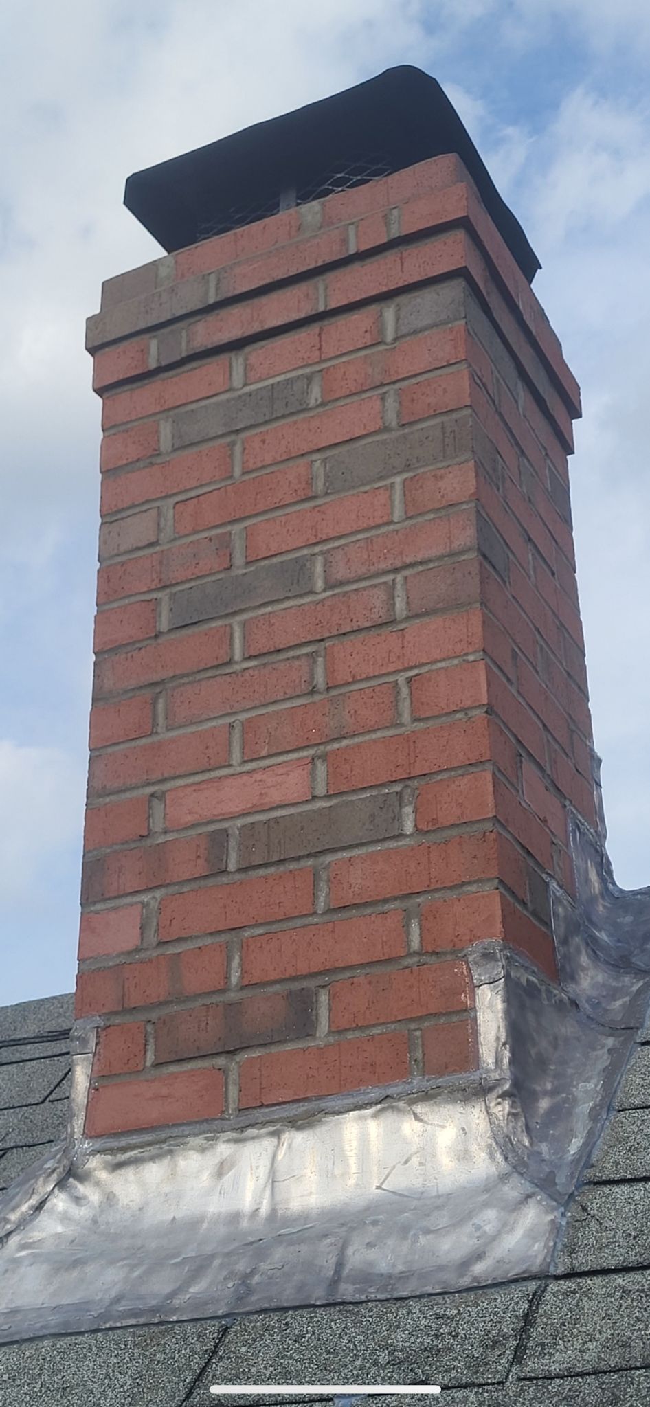 A brick chimney is sitting on top of a roof