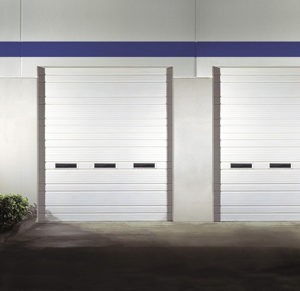 A row of white garage doors on the side of a building