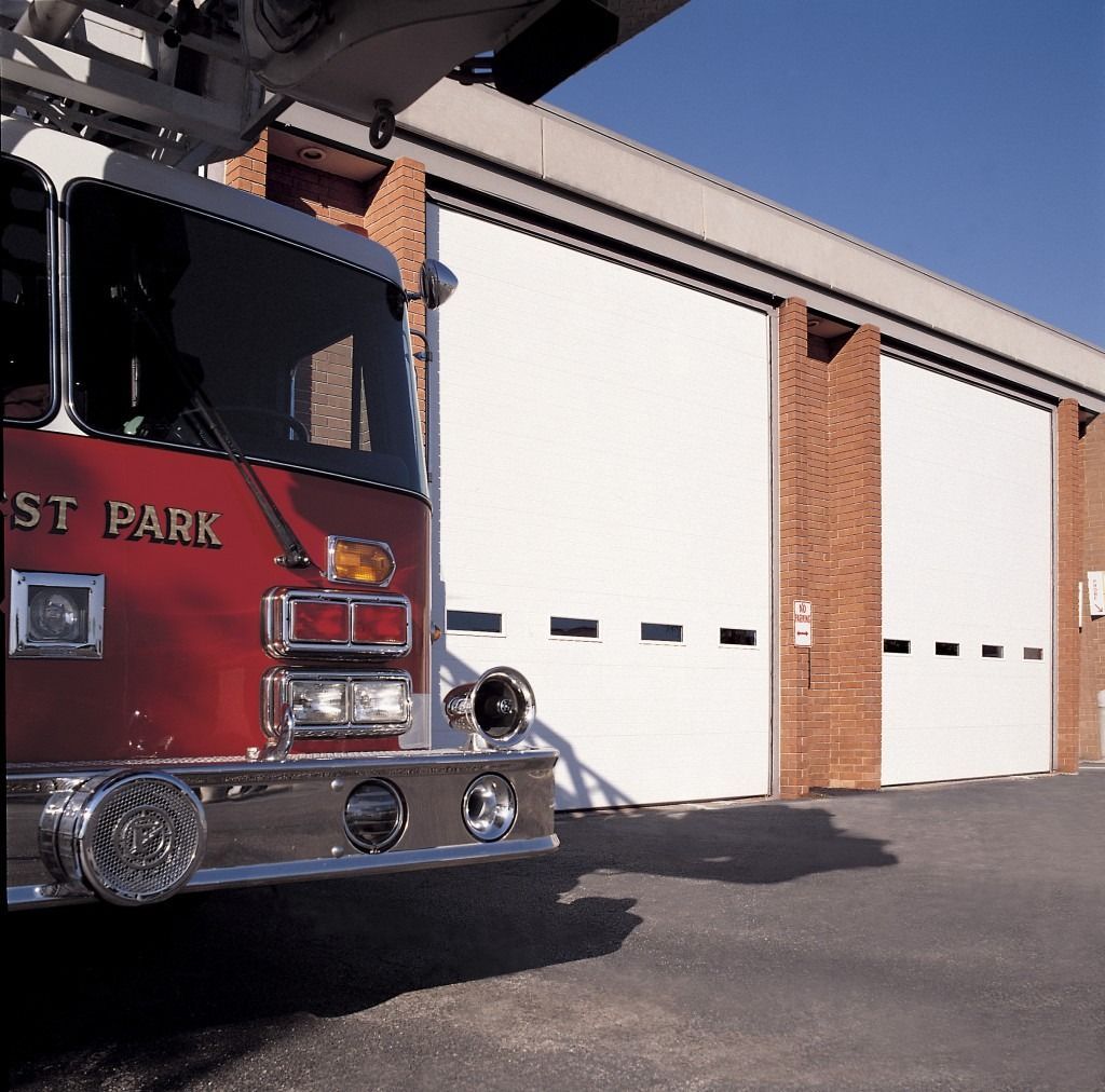 A red fire truck is parked in front of a building that says first park