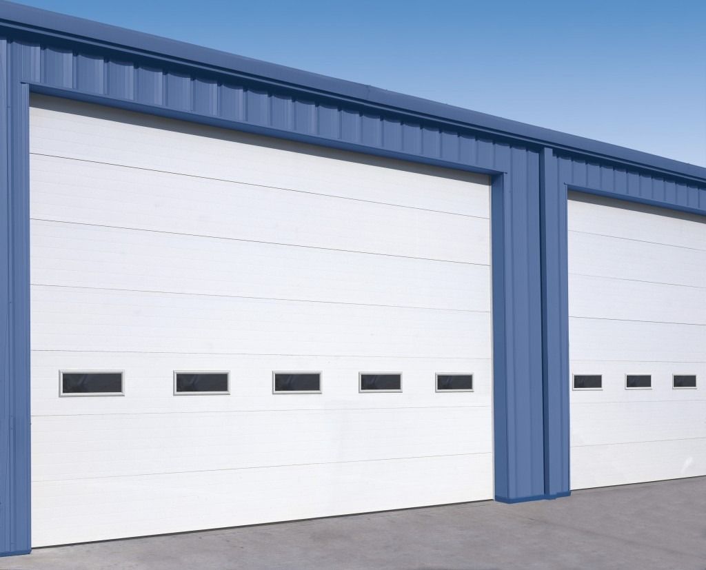 A row of white garage doors on a blue building