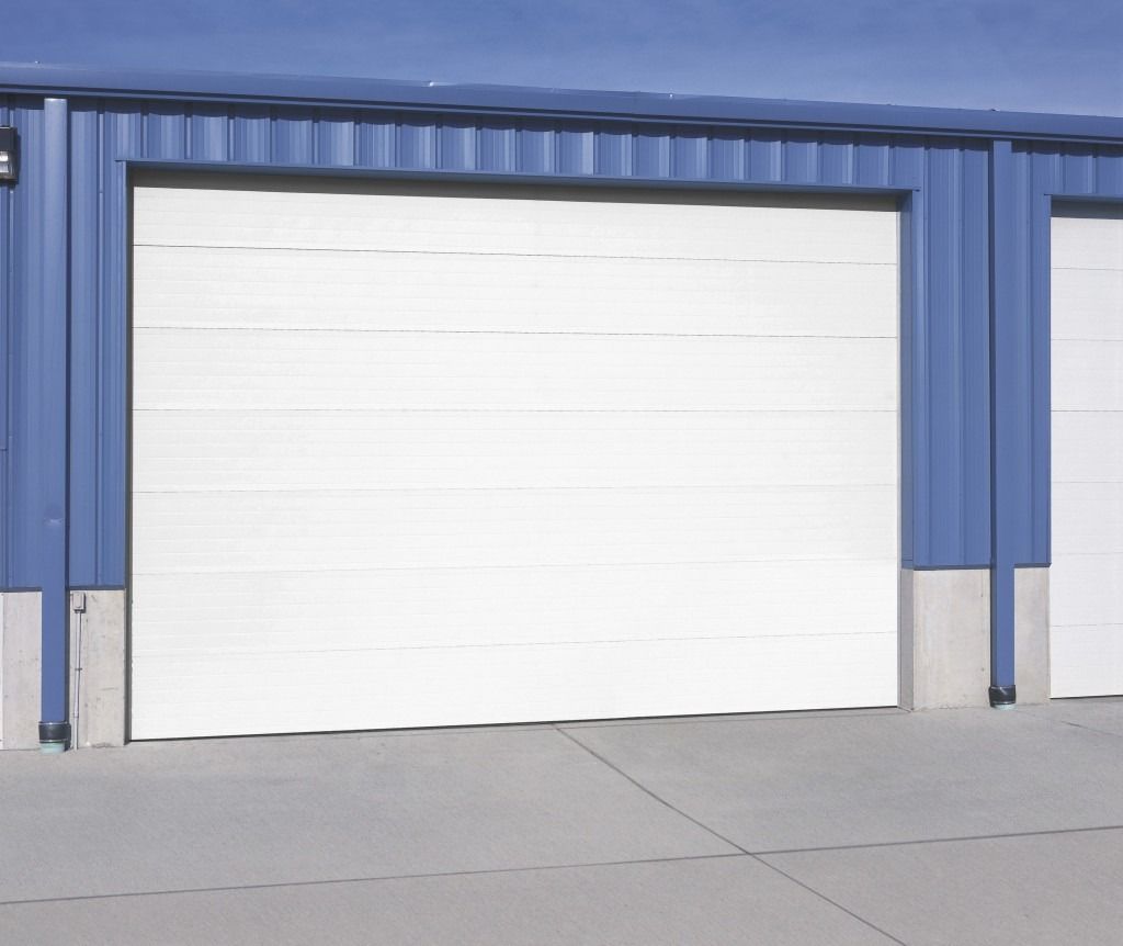 A row of white garage doors on a blue building