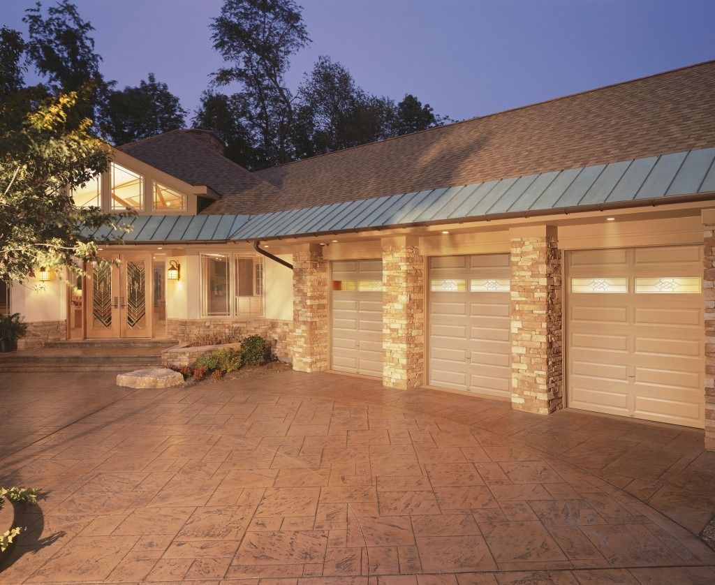 A large house with three garage doors and a copper roof