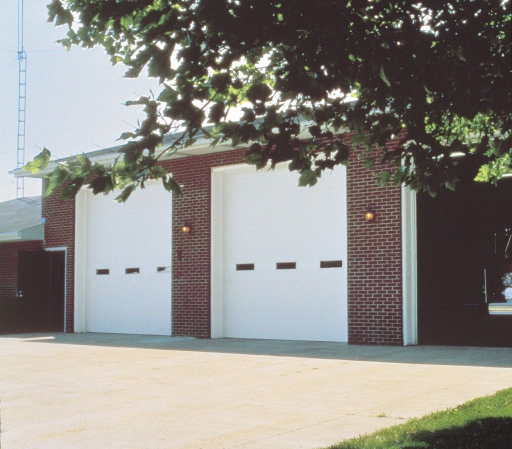 A brick building with three white garage doors