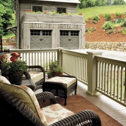 A porch with wicker furniture and a garage in the background