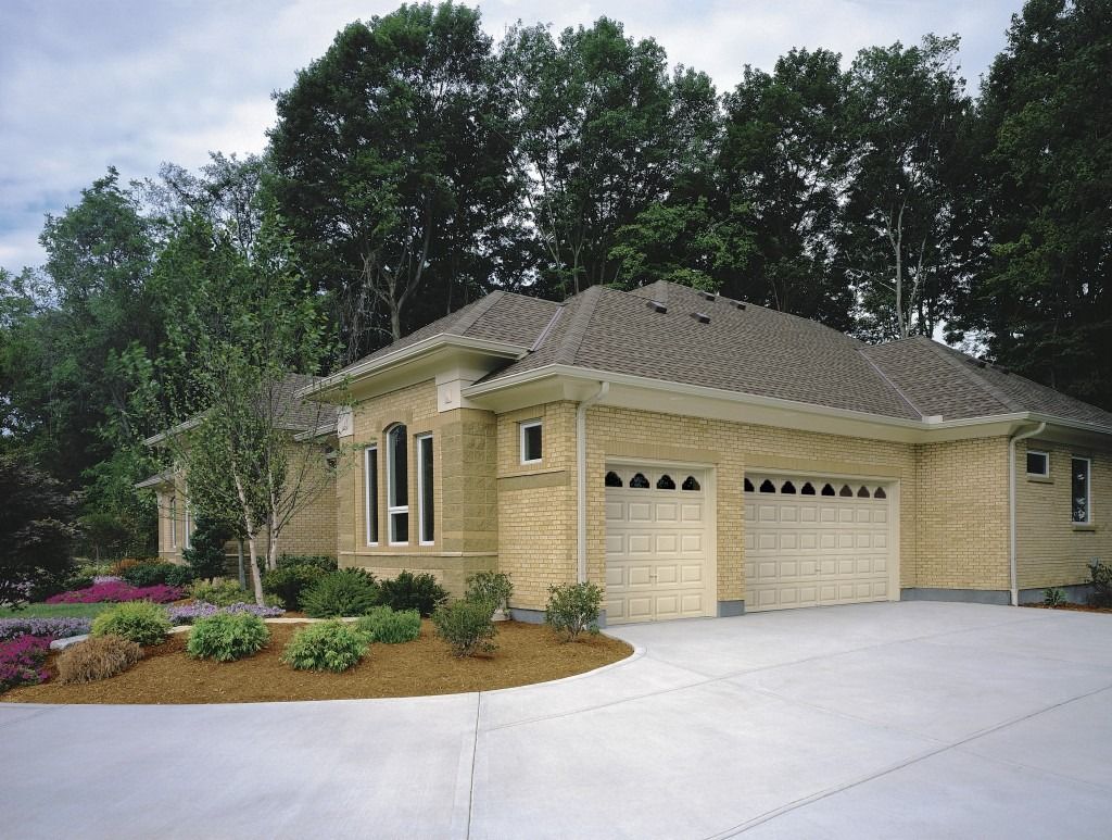 A brick house with two garage doors and a driveway