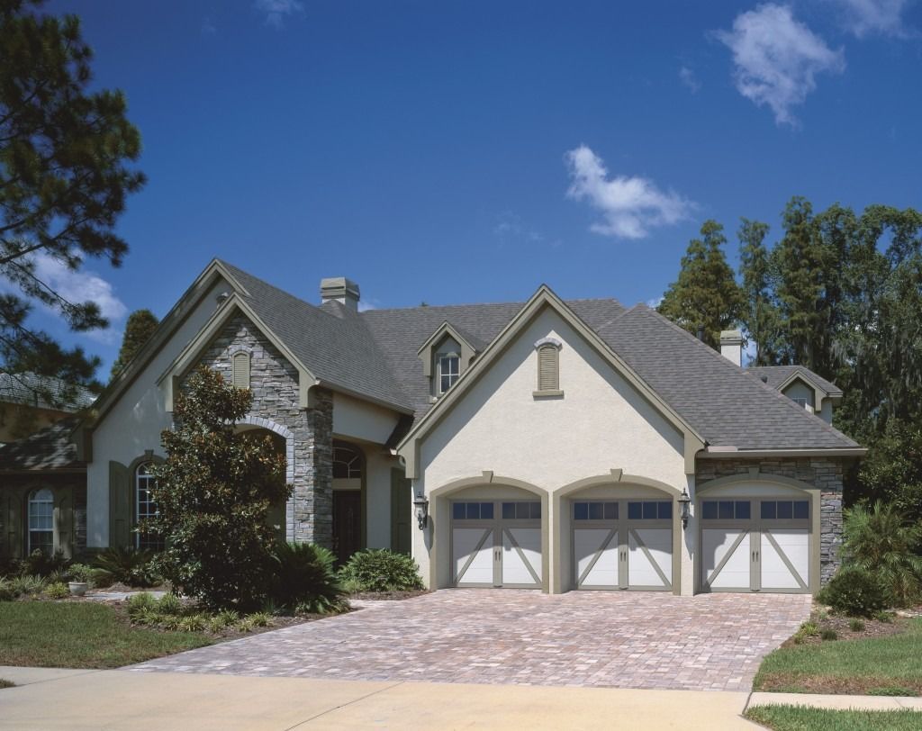 A large house with two garage doors and a brick driveway