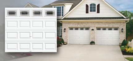 A white garage door is sitting in front of a brick house.