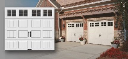 A picture of a white garage door next to a brick house.