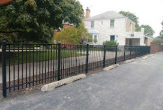 A black metal fence surrounds a white house
