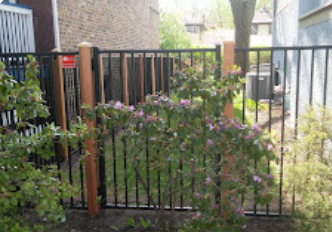 A wrought iron fence with wooden posts in front of a house
