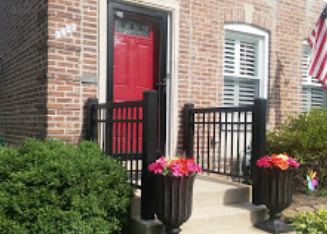 A brick house with a red door and a black fence