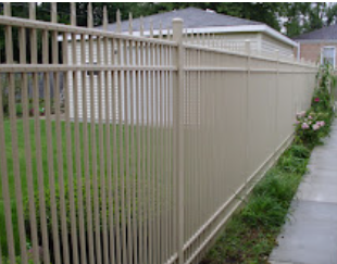 A white metal fence surrounds a yard next to a sidewalk