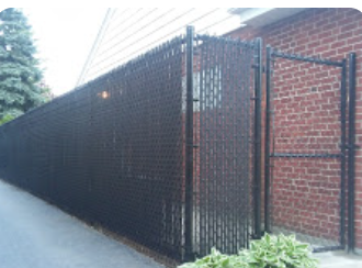 A black chain link fence with a gate in front of a brick building