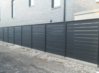 A black fence is along the side of a building