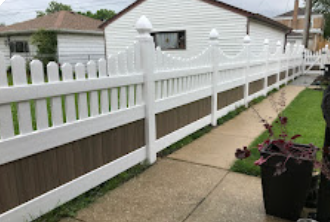 A white and brown fence along a sidewalk in front of a house