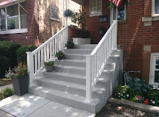 A white railing on a set of stairs leading up to a brick house