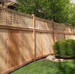 A wooden fence surrounds a lush green yard