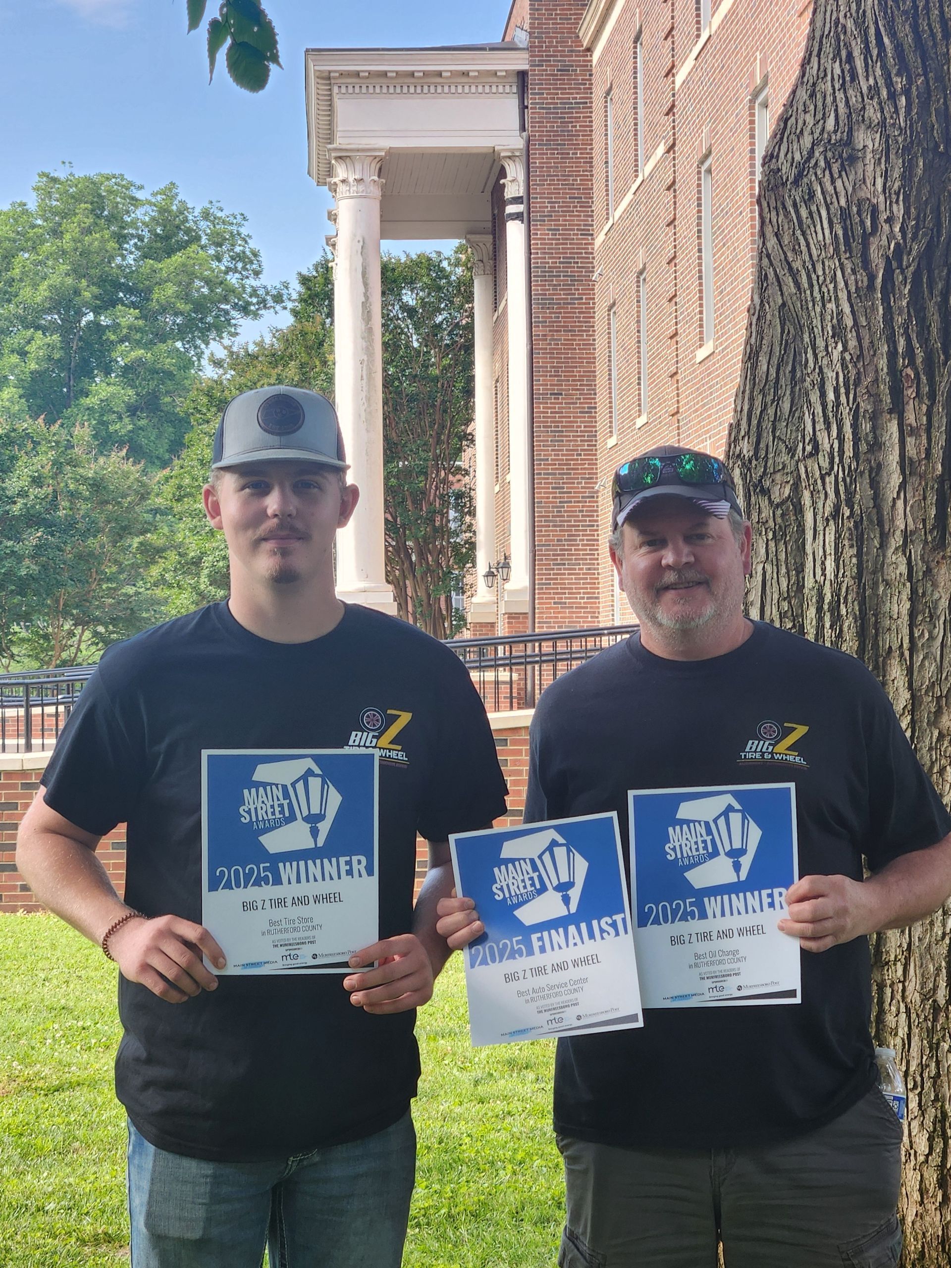 Two men are standing next to each other holding signs in front of a building.
