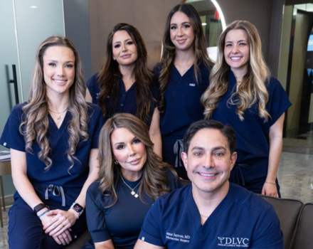 Medical staff pose for a photo in blue scrubs. Smiling faces, modern office setting.