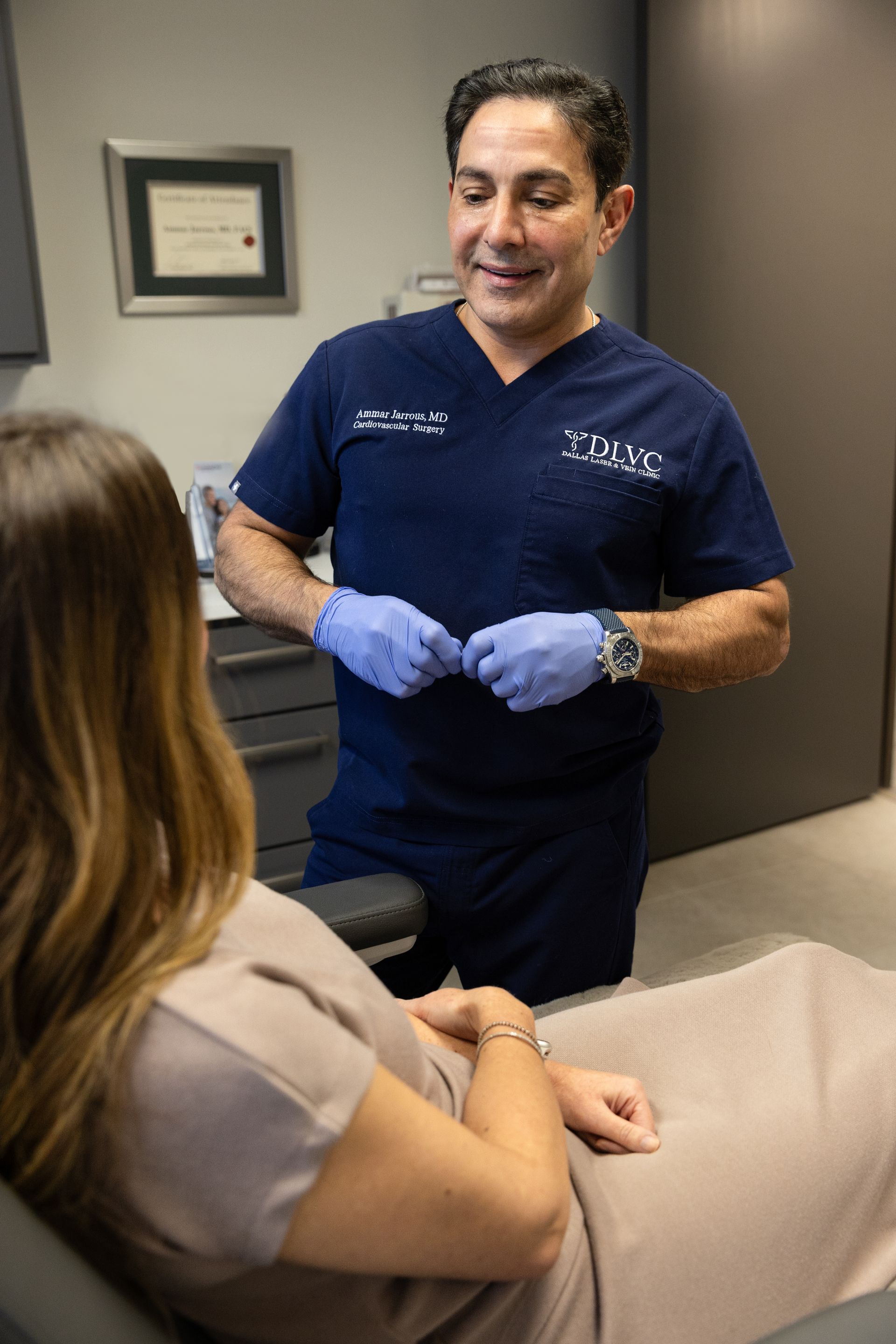 Doctor in blue scrubs talks to a patient in an office.