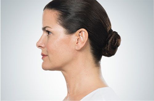 Side profile of a person with dark hair styled in a low bun, set against a plain light gray background.