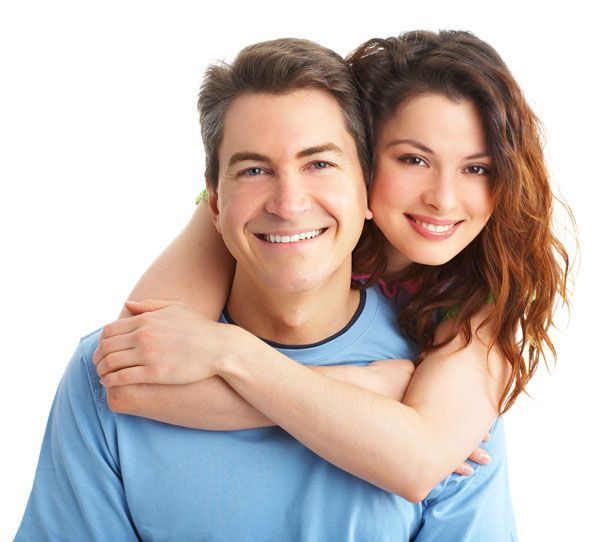 Smiling couple hugging, with the woman leaning over the man’s shoulders on a white background