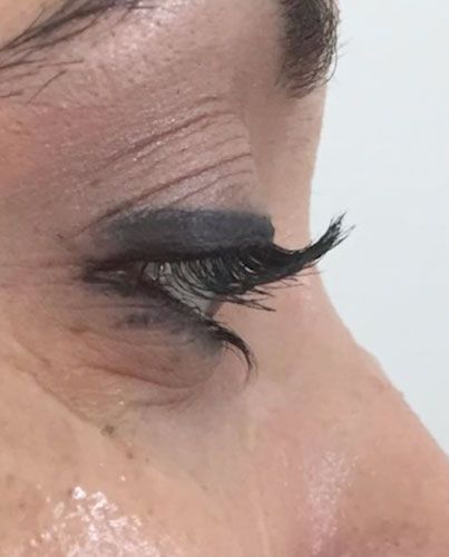 Close-up side profile of an eye with long black eyelashes and dark eye makeup