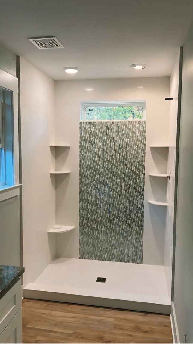 A bathroom with a walk-in shower and shelves