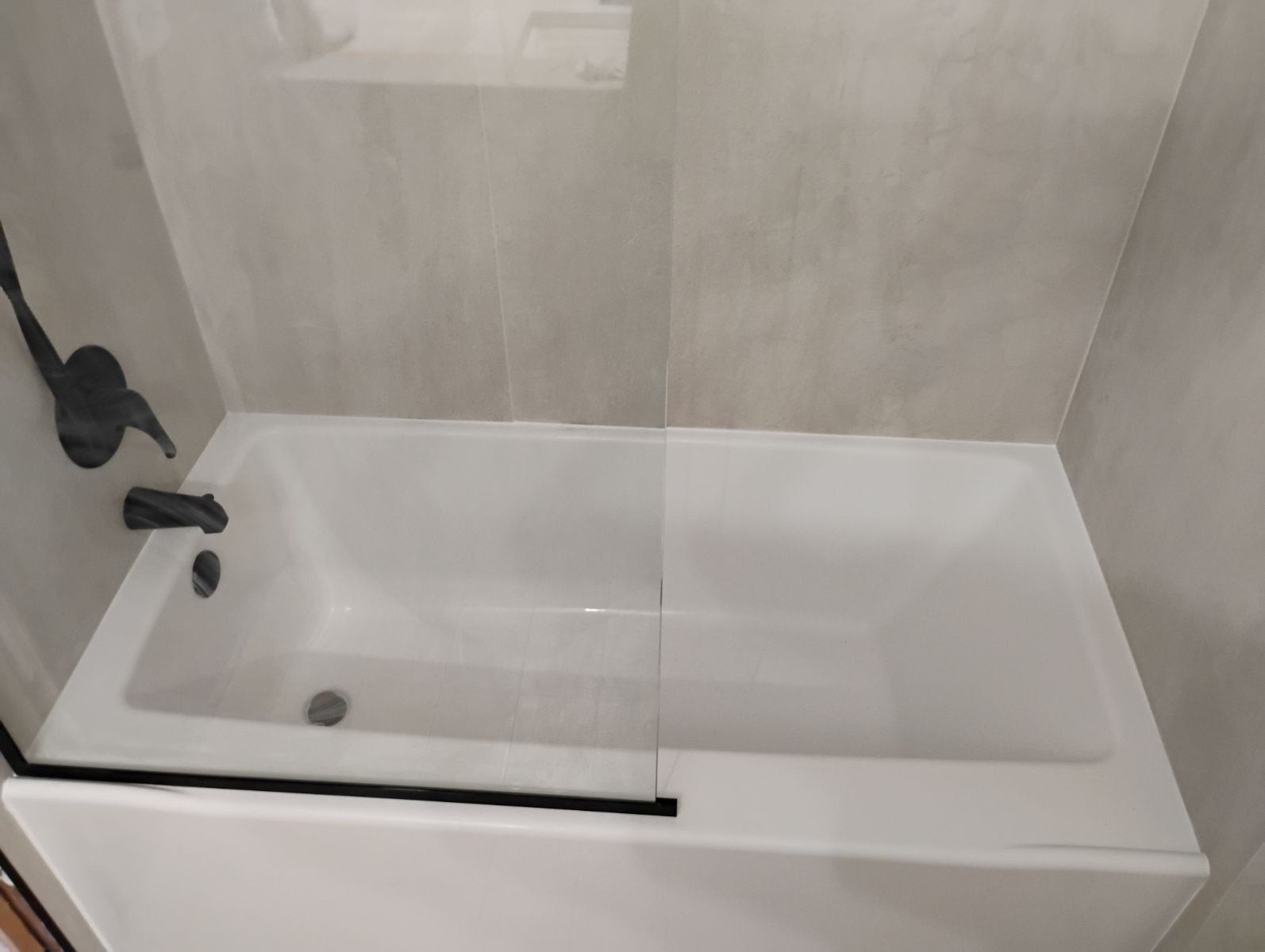 A bathtub with a glass shower door in a bathroom