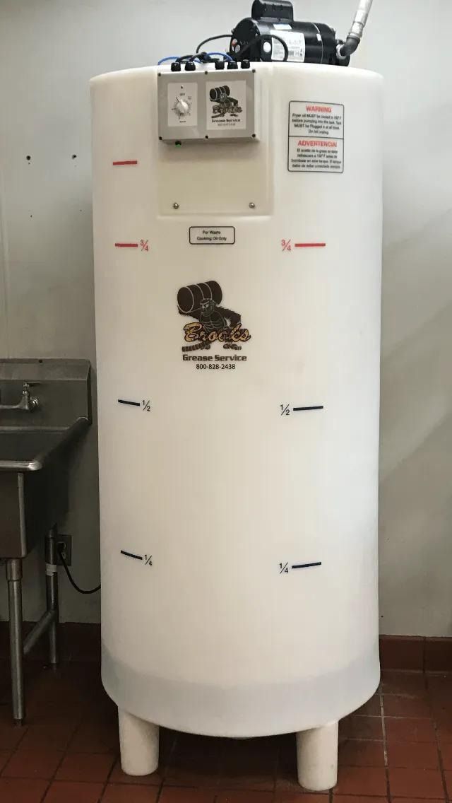 White cylindrical tank with black pump, level markers, and logos, in an indoor setting.