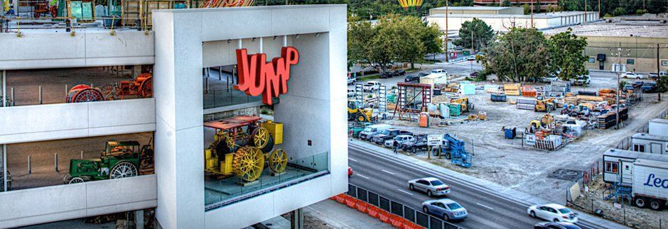 an aerial view of a building with a lot of cars parked in front of it .