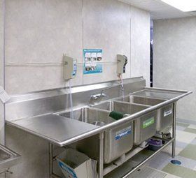 a kitchen with two sinks and a soap dispenser on the wall .