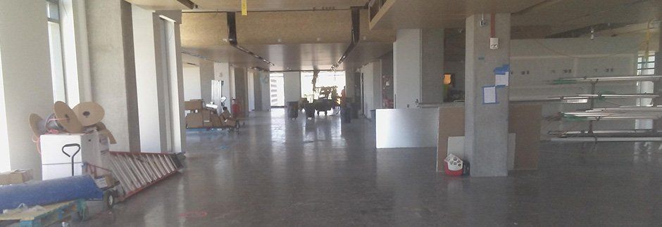 a long hallway in a building with a lot of windows and boxes on the floor .