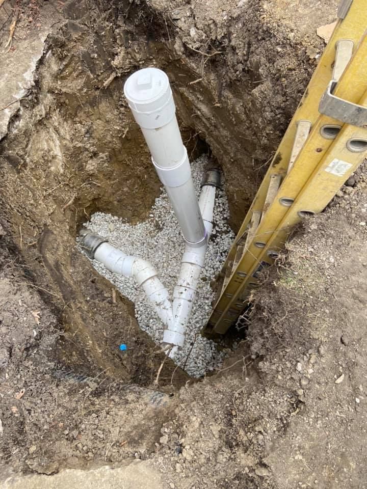 A ladder is sitting next to a pipe in the dirt.