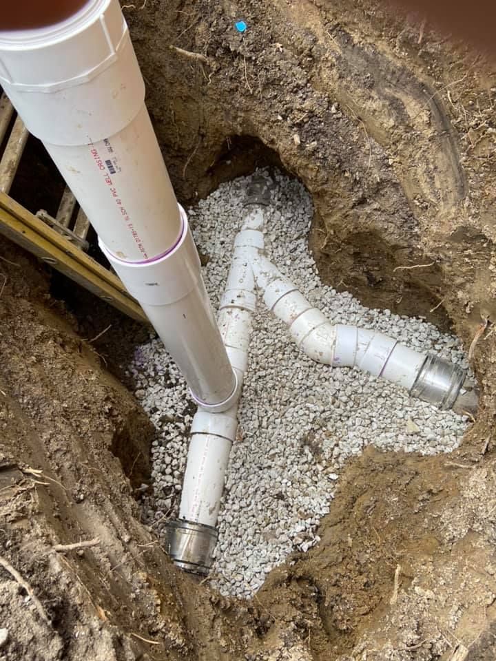 A drain pipe is being installed in a hole in the ground.