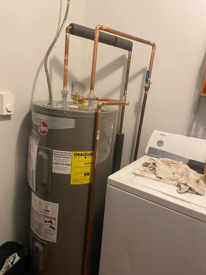A water heater is sitting next to a washer and dryer in a laundry room.