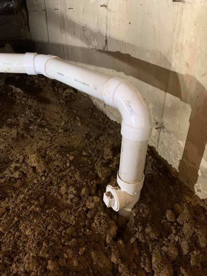 A white pipe is sitting on top of a pile of dirt.