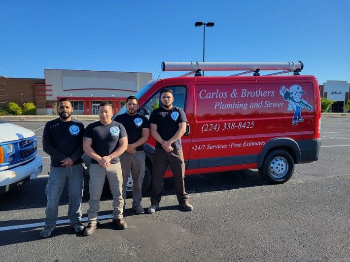 A group of men are standing in front of a red van that says carlos & brothers plumbing and sewer.
