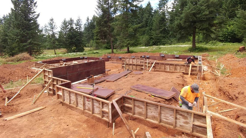 A man is working on a construction site with trees in the background.