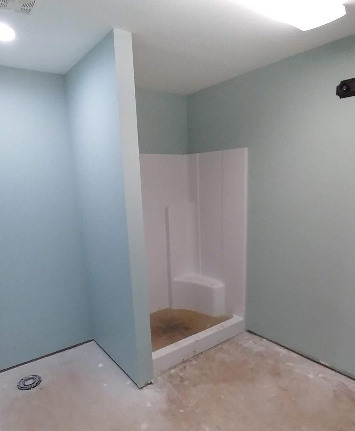 A bathroom with blue walls and a white shower stall.