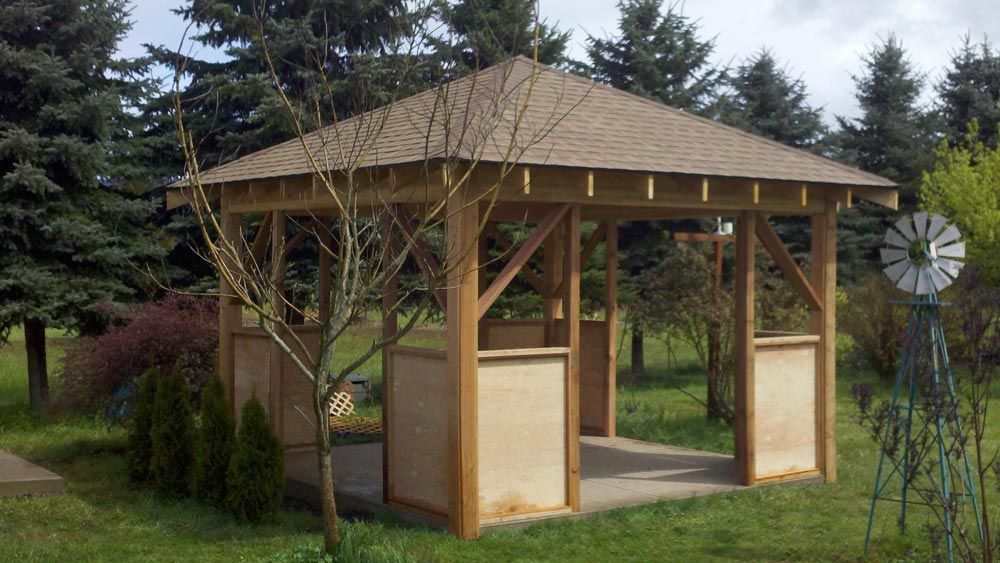 A wooden gazebo is sitting in the middle of a lush green field.