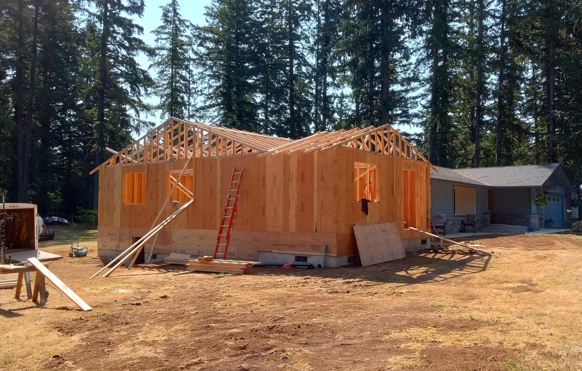 A house is being built in a field with trees in the background