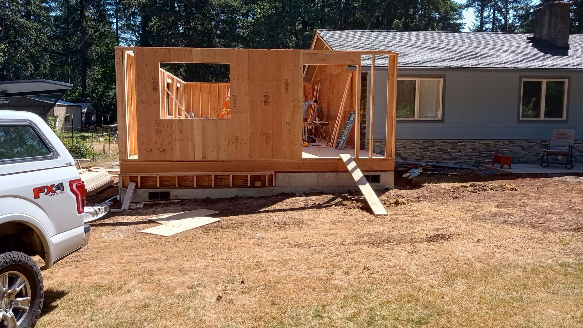 A white truck is parked in front of a house under construction.