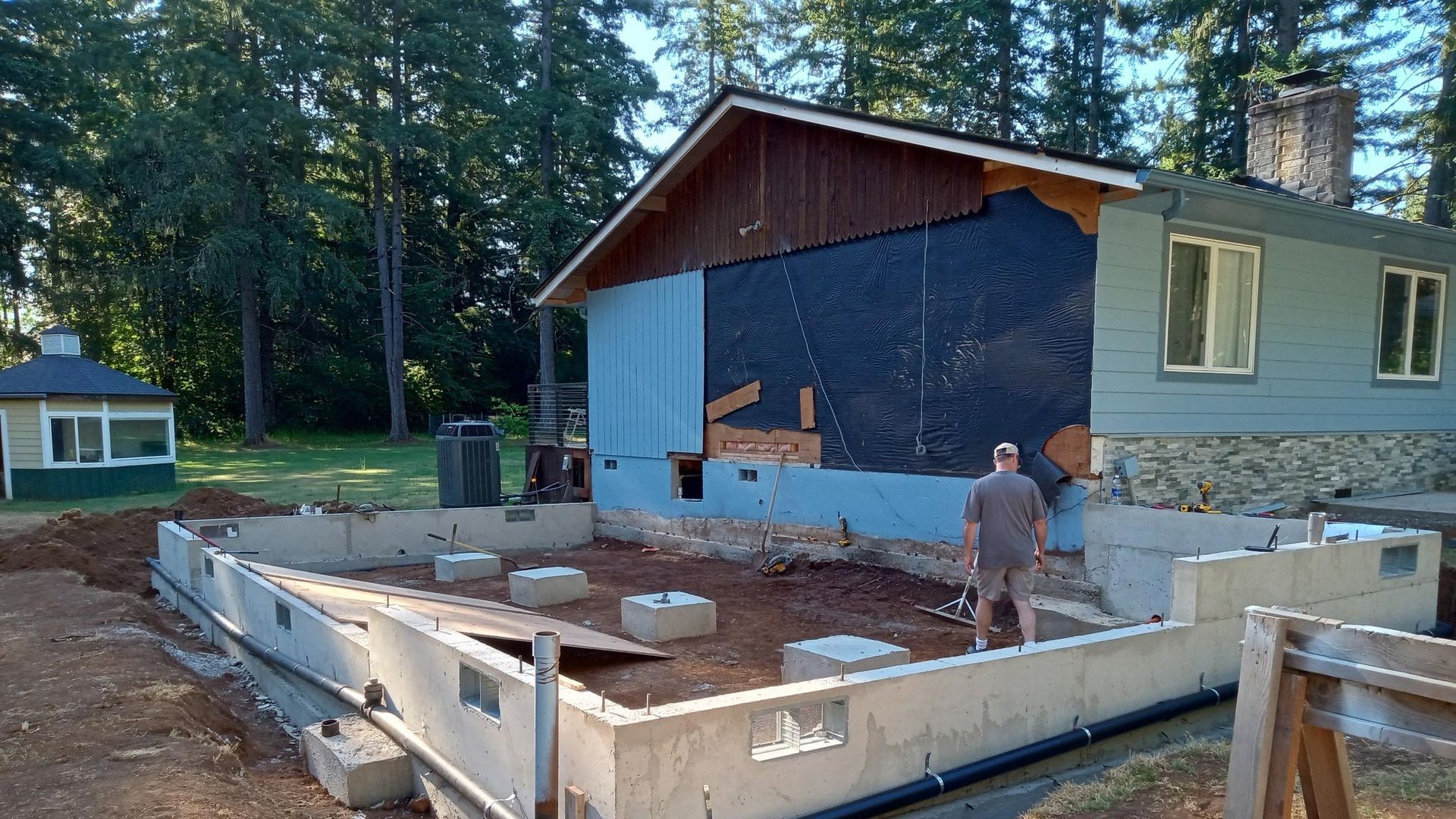 A man is standing in front of a house that is being remodeled.