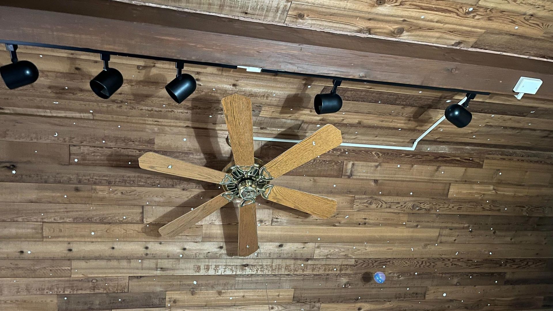 A ceiling fan is hanging from the ceiling of a wooden room.