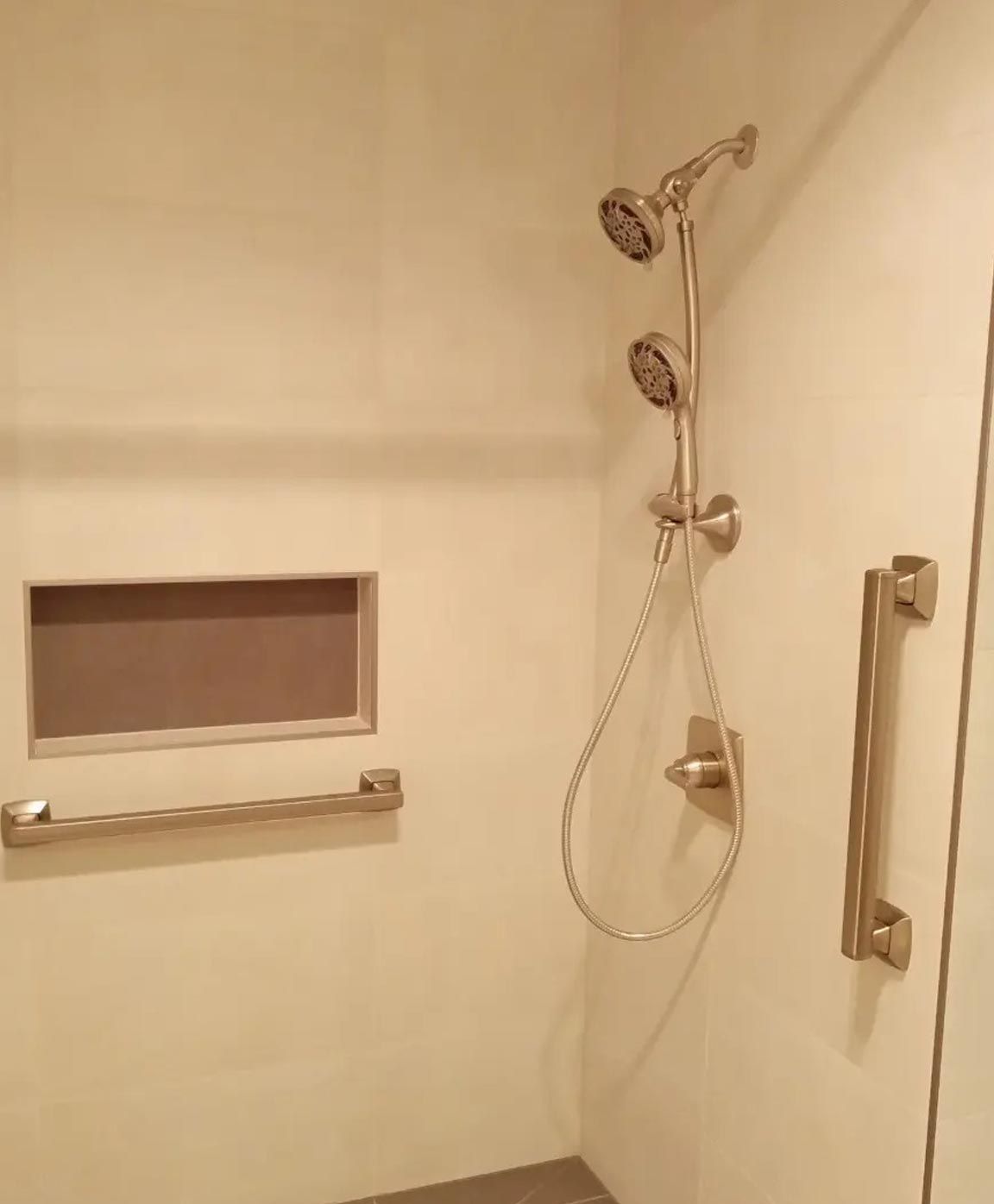 A shower with three shower heads and a stainless steel handle